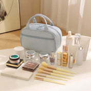 Borsa cosmetica azzurra con set di trucchi: pennelli, ombretti, rossetti, smalti e creme su tavolo bianco. Accessori bellezza eleganti e moderni.