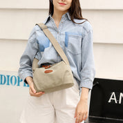 Donna con camicia di jeans e borsa a tracolla beige, stile casual. Moda femminile, accessori eleganti, abbigliamento estivo.