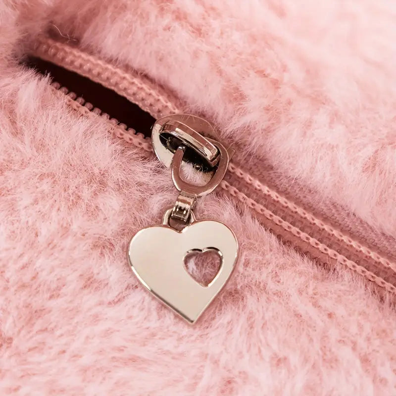 Cerniera con ciondolo a forma di cuore in metallo su tessuto peluche rosa. Accessorio moda elegante, dettagli di lusso, stile romantico.