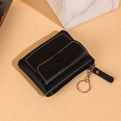Portafoglio nero in pelle con cuciture bianche, chiusura a bottone e cerniera, anello portachiavi. Accessorio moda elegante e pratico.