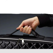 Mano che tiene una borsa nera trapuntata con cerniera, design elegante e moderno. Accessorio moda, borsa a mano, stile sofisticato.