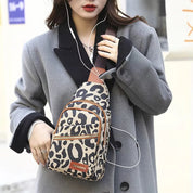 Donna con borsa a tracolla leopardata, cappotto grigio, auricolari. Moda urbana, accessori trendy, stile casual.