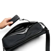 Borsa a tracolla nera con tasca aperta, mano che inserisce un portafoglio nero. Design elegante, ideale per lavoro e viaggio. Accessori moda uomo.