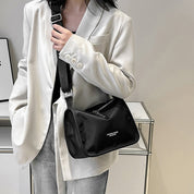 Donna con giacca bianca indossa borsa a tracolla nera elegante, design moderno, perfetta per moda urbana e casual. Accessorio versatile e chic.