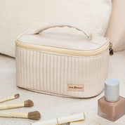 Borsa cosmetica beige con manico, design trapuntato, zip, pennelli trucco e smalto. Ideale per organizzare prodotti di bellezza.
