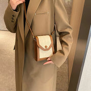 Cappotto beige elegante con borsa a tracolla marrone e bianca, design moderno, moda autunno inverno, accessorio donna chic.