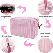 Astuccio da viaggio in seersucker di cotone rosa a righe, con cerniere robuste, manico pratico e ampio spazio interno. Perfetto per organizzare cosmetici.