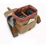 Borsa fotografica in tela beige con tracolla, scomparti per fotocamera e obiettivo, tasca esterna per smartphone. Accessorio pratico e resistente.