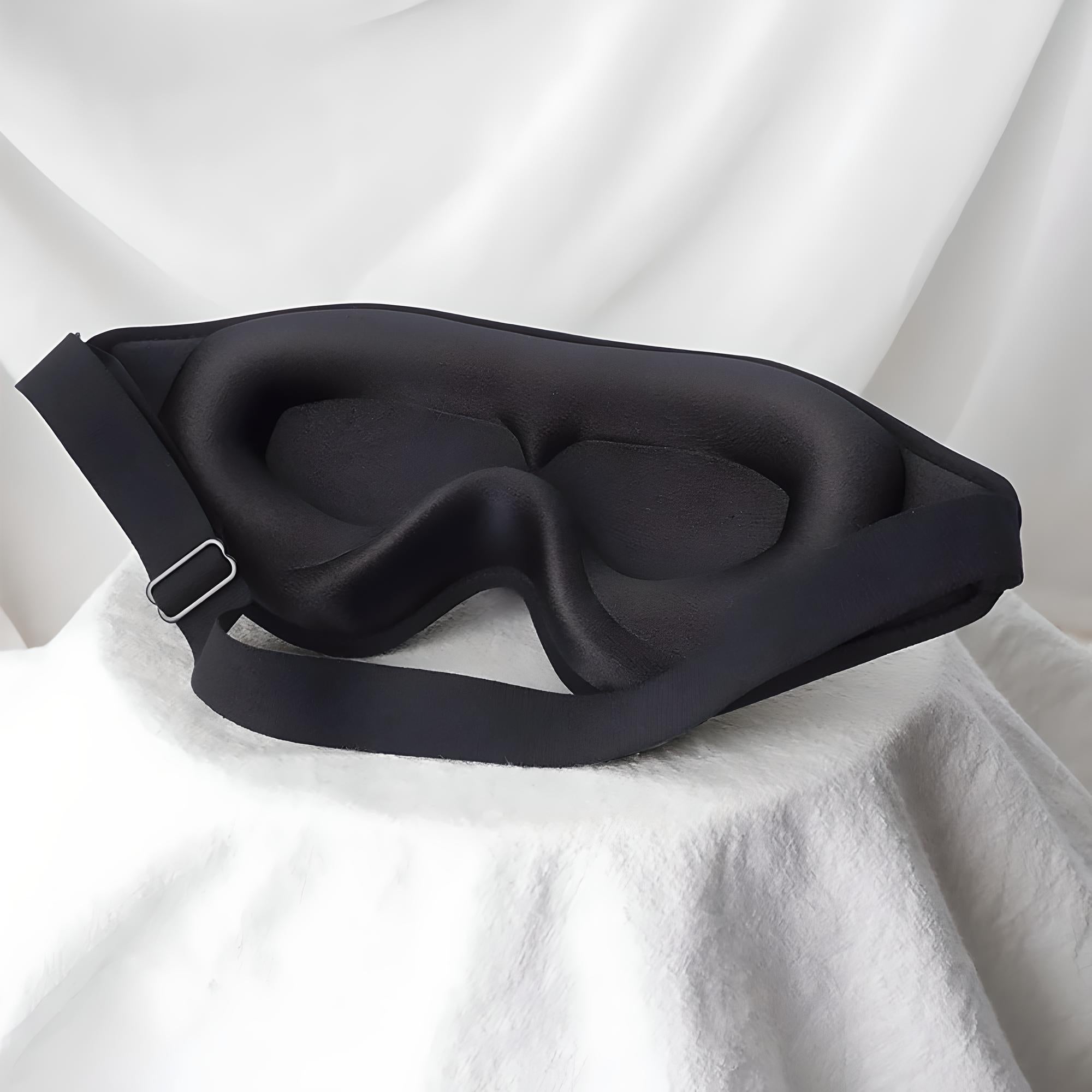 Maschera per dormire nera in memory foam su sfondo bianco, design ergonomico, cinturino regolabile, ideale per bloccare la luce e migliorare il sonno.