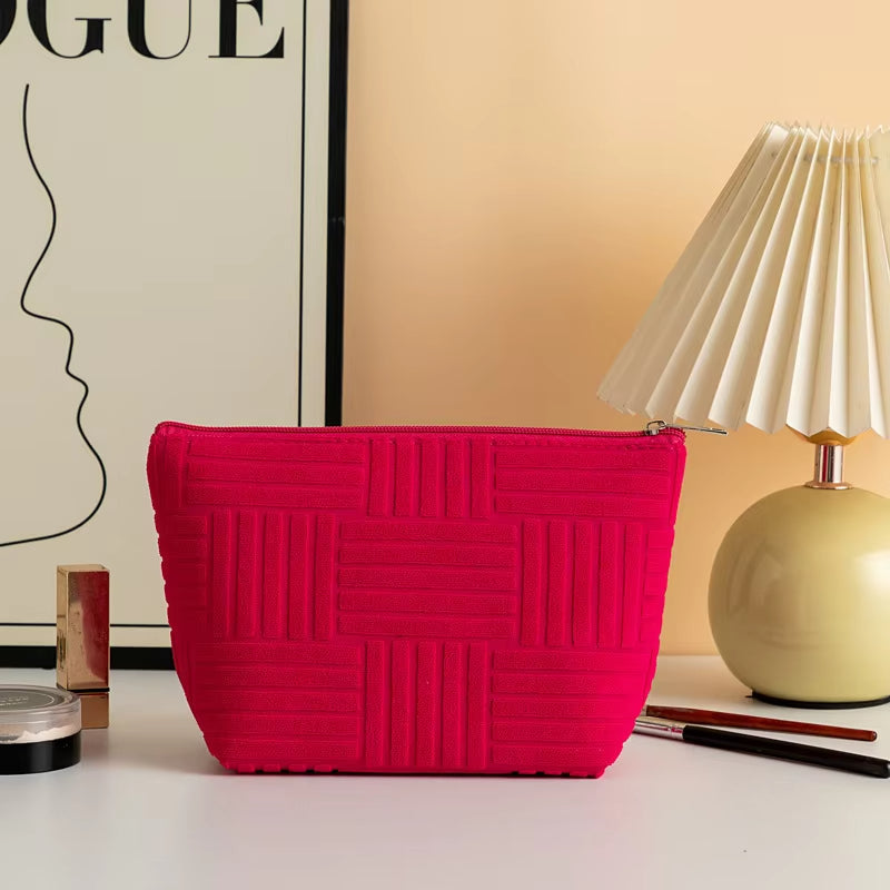 Pochette rossa elegante su tavolo bianco, accanto a lampada moderna e decorazioni minimaliste. Accessorio moda donna, design geometrico.