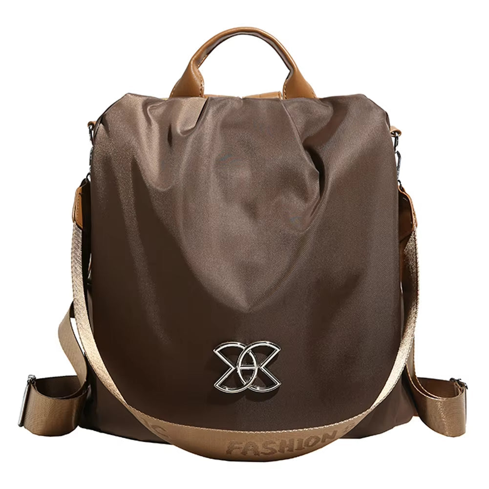 Zaino moda marrone in nylon con manico superiore, tracolla regolabile e decorazione metallica frontale. Accessorio elegante e funzionale per donna.