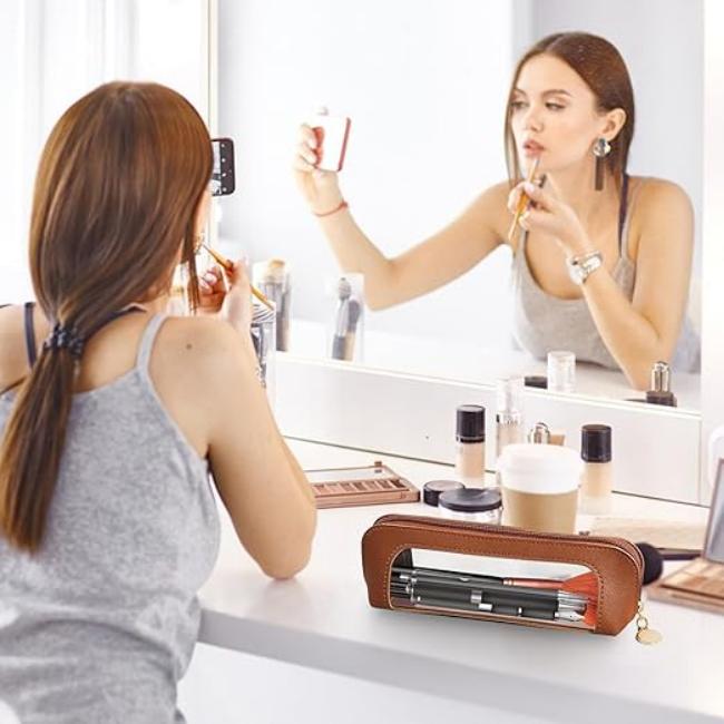 Donna che si trucca davanti a uno specchio, con astuccio in pelle per trucchi in primo piano. Accessori make-up, routine bellezza, cosmetici.