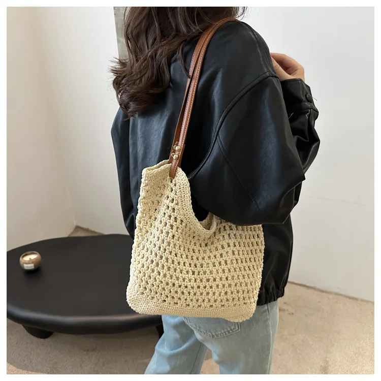 Donna con borsa a tracolla in maglia beige, giacca nera e jeans. Accessorio moda casual, stile boho chic, perfetto per shopping e uscite quotidiane.