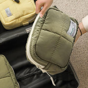 Mano che inserisce un organizer da viaggio verde in valigia aperta, accanto a un organizer giallo. Ideale per organizzare bagagli e accessori.