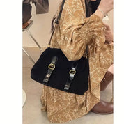 Donna con abito marrone floreale e borsa nera in pelle con fibbie dorate. Moda autunnale, accessori eleganti, stile casual chic.