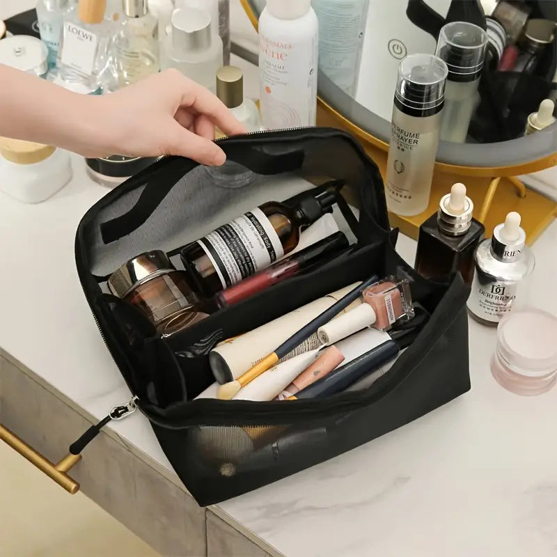 Borsa trucco nera con cosmetici e pennelli su tavolo da toeletta, specchio rotondo, prodotti skincare, organizzazione beauty, accessori make-up.