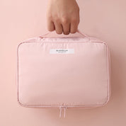 Borsa trucco rosa con manico, chiusura a zip, design compatto. Ideale per organizzare cosmetici e accessori di bellezza.