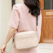 Donna con borsa a tracolla beige in pelle, design elegante, indossa abito rosa. Accessorio moda femminile, perfetto per look casual e chic.