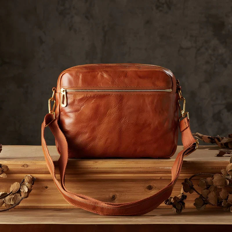 Borsa a tracolla in pelle marrone, design elegante con cerniera dorata, ideale per moda uomo e donna, accessorio di tendenza autunno inverno.