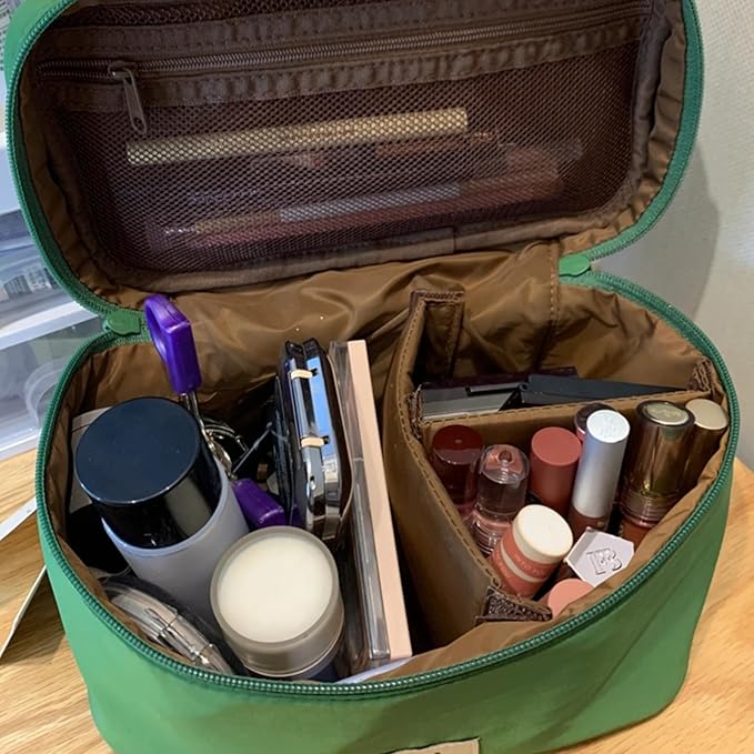Borsa trucco verde aperta con vari cosmetici: rossetti, ombretti, mascara e pennelli. Organizzazione perfetta per il make-up quotidiano.