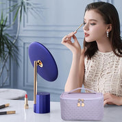 Donna che si trucca davanti a uno specchio da tavolo blu, con rossetto rosso e borsa cosmetica viola. Eleganza, bellezza, accessori trucco.
