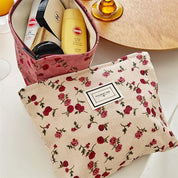 Beauty case floreale con prodotti cosmetici, tra cui crema solare e trucco, su tavolo bianco. Elegante e pratico per viaggi e organizzazione.