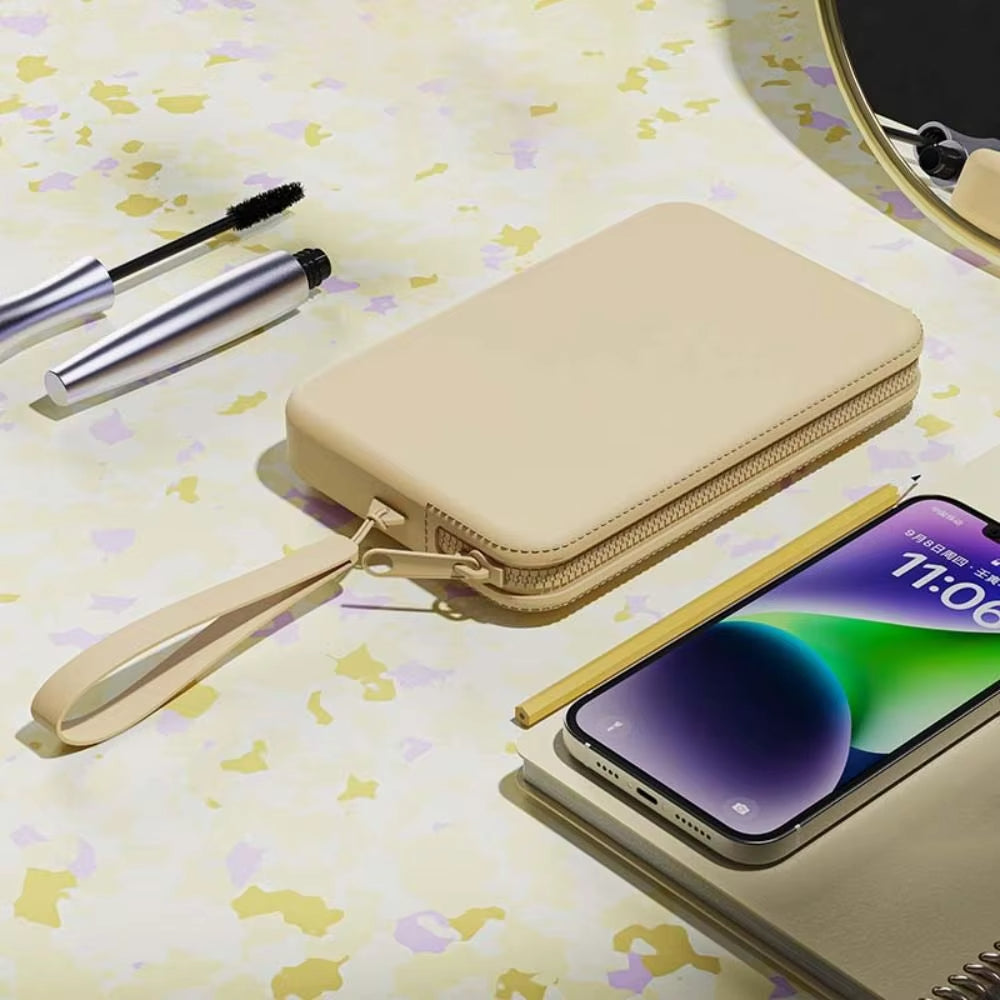 Custodia portafoglio beige in pelle per smartphone su tavolo con specchio, mascara e matita. Accessorio elegante e funzionale per dispositivi mobili.
