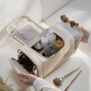 Borsa organizer cosmetici beige aperta, con scomparti per pennelli trucco, flaconi e accessori beauty. Ideale per viaggi e organizzazione trucco.