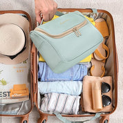 Valigia aperta con abiti estivi, cappello, sandali e beauty case verde acqua. Ideale per viaggi, organizzazione bagagli, accessori da viaggio.