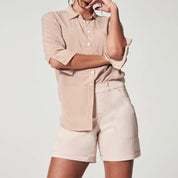 Camicia a righe beige e bianche con maniche arrotolate, abbinata a shorts beige. Moda casual donna, abbigliamento estivo elegante.