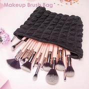 Borsa porta pennelli trucco nera con cerniera, contenente vari pennelli cosmetici rosa e neri. Accessorio essenziale per il make-up.