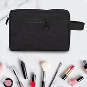 Borsa da toilette nera su sfondo bianco con accessori trucco: rossetti, pennelli, smalti. Ideale per organizzare cosmetici e prodotti di bellezza.