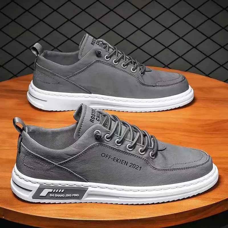 Scarpe da ginnastica grigie da uomo su tavolo in legno, design moderno, suola bianca, lacci grigi, adatte per moda casual e sportiva.