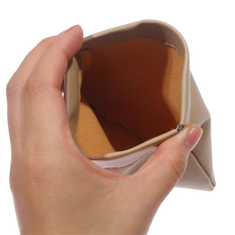 Mano che tiene un portamonete beige in pelle sintetica, aperto, con interno marrone. Accessorio moda, elegante e pratico per donna.