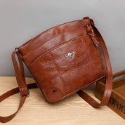 Borsa a tracolla in pelle marrone, design elegante con logo metallico, ideale per moda donna. Accessorio versatile e di tendenza.