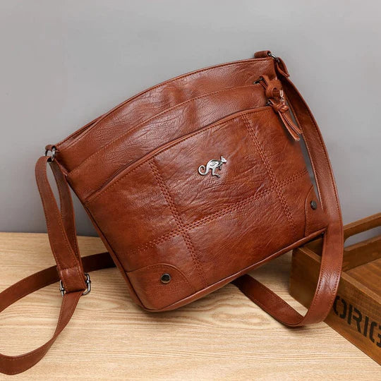 Borsa a tracolla in pelle marrone, design elegante con logo metallico, ideale per moda donna. Accessorio versatile e di tendenza.