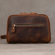 Borsa da toilette in pelle marrone con cerniera frontale, design elegante e resistente, ideale per viaggi e organizzazione accessori personali.