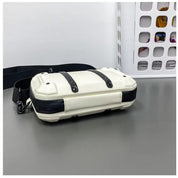 Borsa a tracolla bianca e nera su tavolo grigio, design moderno con cinghie regolabili. Accessorio moda unisex, ideale per uso quotidiano.