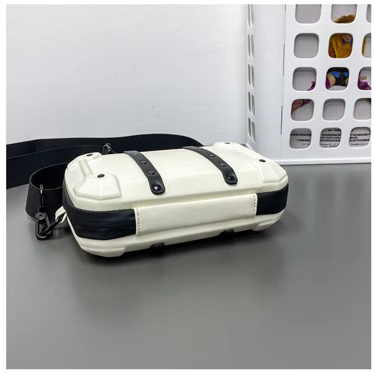 Borsa a tracolla bianca e nera su tavolo grigio, design moderno con cinghie regolabili. Accessorio moda unisex, ideale per uso quotidiano.