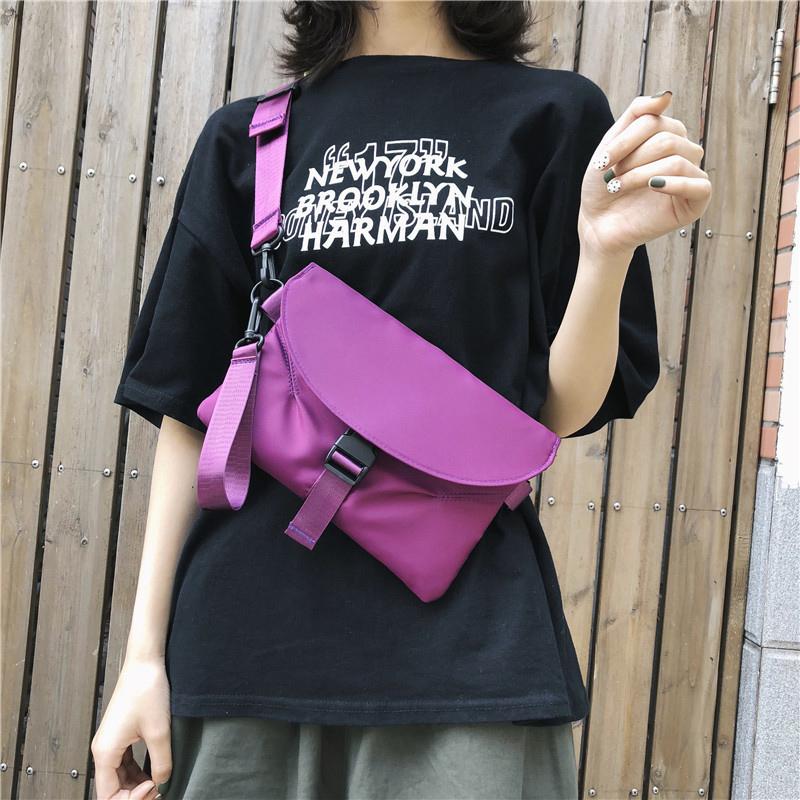 Donna con borsa a tracolla viola, maglietta nera con scritta bianca. Accessorio moda casual, stile urbano, perfetto per uscite quotidiane.