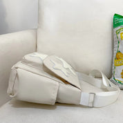 Marsupio bianco su divano bianco, design moderno, con chiusura a zip e cintura regolabile. Accessorio moda unisex, ideale per viaggi e attività all'aperto.