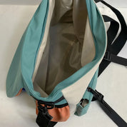 Zaino aperto verde acqua e beige, design moderno, tasche multiple, cerniere nere, ideale per viaggi e uso quotidiano.