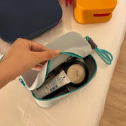 Astuccio da viaggio aperto con cosmetici, tra cui crema e cipria. Design compatto, ideale per organizzare prodotti di bellezza.
