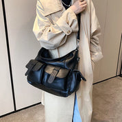 Cappotto beige con borsa a tracolla nera in pelle, tasche frontali con fibbie. Accessorio moda elegante e pratico per donna.