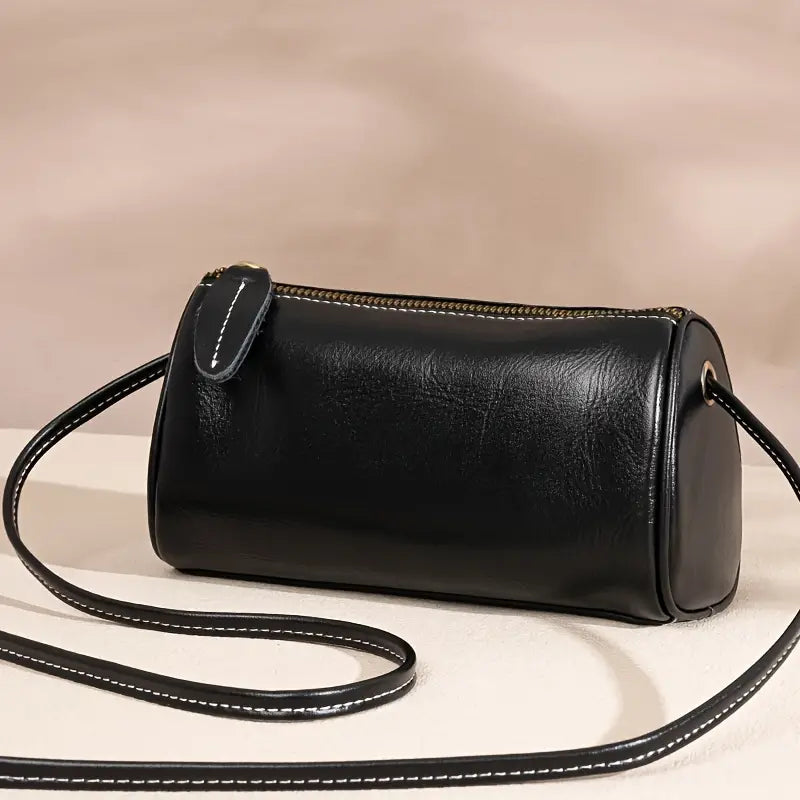 Borsa a tracolla cilindrica in pelle nera, design elegante con cerniera dorata, ideale per moda donna, accessorio versatile e chic.