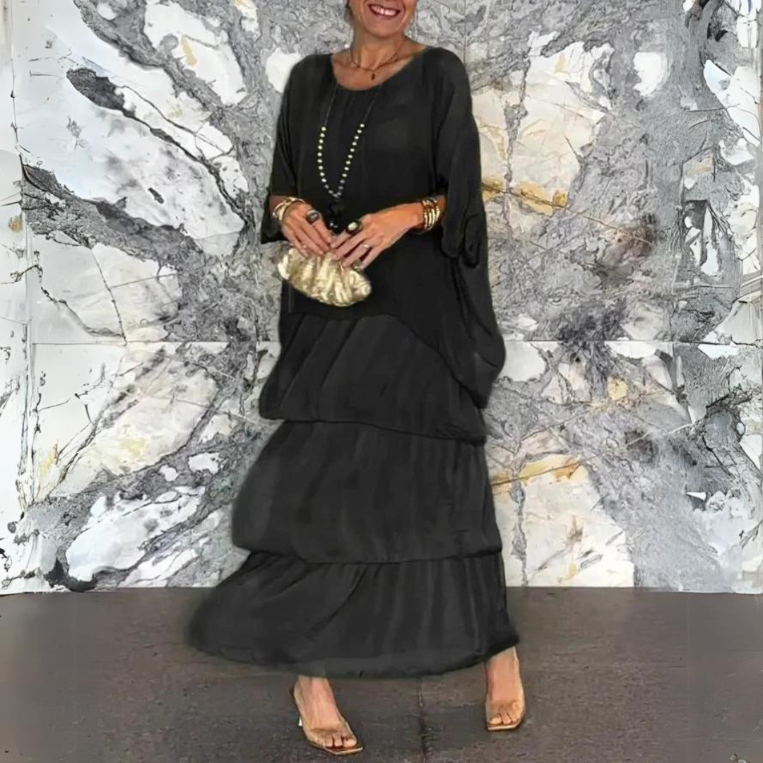 Donna in abito nero elegante con collana e borsa dorata, sfondo marmo artistico. Moda femminile, abbigliamento chic, accessori glamour.