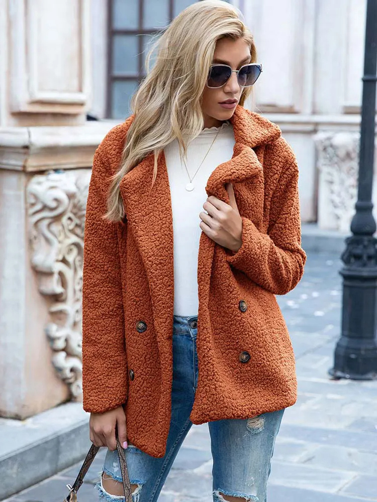Donna con cappotto teddy arancione, jeans strappati e occhiali da sole. Moda autunnale, abbigliamento casual chic, look urbano elegante.