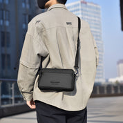 Uomo con camicia beige e borsa a tracolla nera Weixier, sfondo urbano. Accessorio moda maschile, stile casual, tendenza 2023.