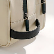 Borsa a tracolla beige con cerniere nere, manico in pelle nera, design elegante e moderno, ideale per moda e accessori di tendenza.
