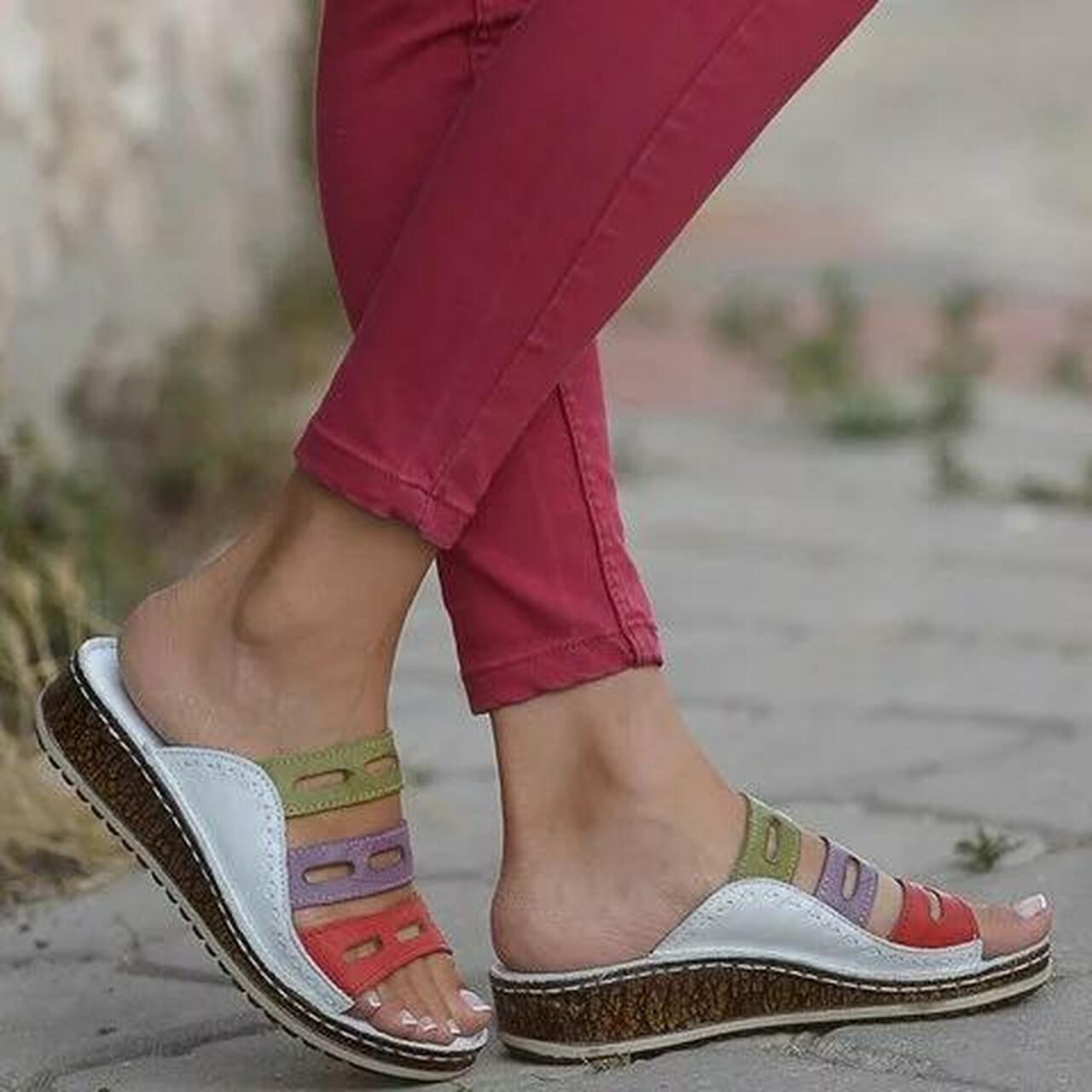 Donna con sandali estivi colorati su suola in sughero, indossa pantaloni rosa. Scarpe comode, moda casual, calzature estive donna.